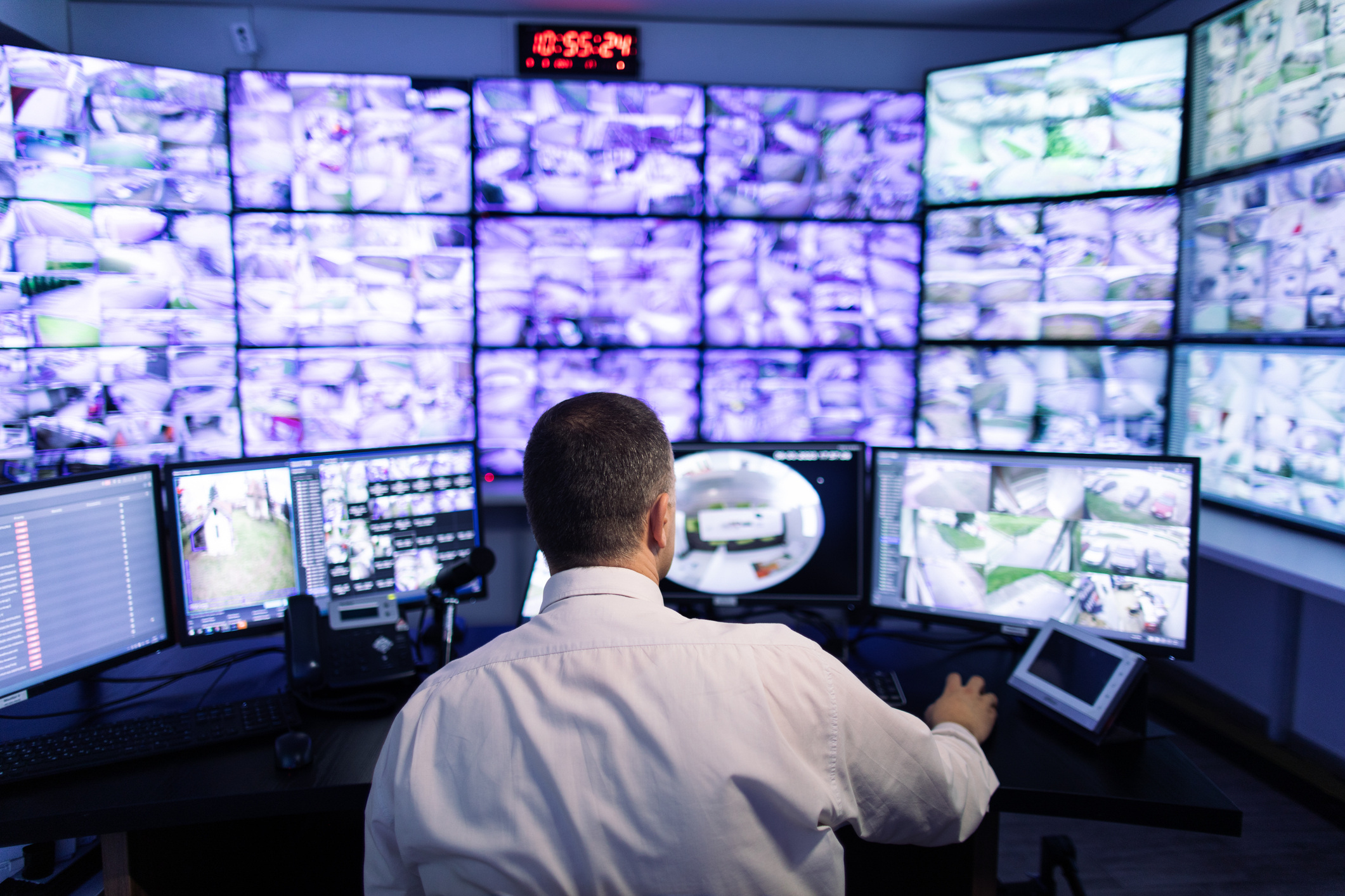Surveillance room with several screens. Man sitting in front managing and overseeing.