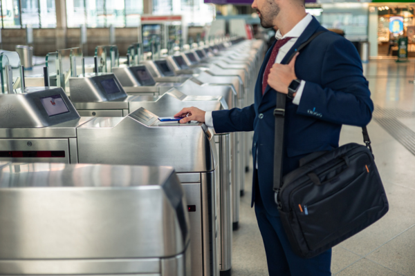 Business man scanning his phone on a public transport ticketing gate. 