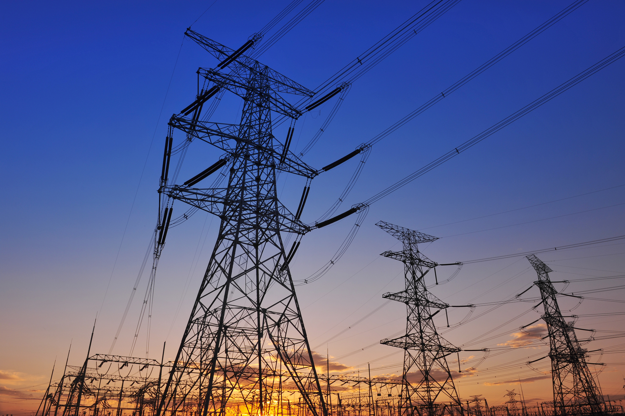 Evening sky backdrop with tall power towers and wires in the foreground. 